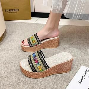 Embroidered platform wedge slides with colorful floral detail and woven wedge heel.