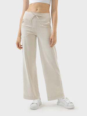 Cream wide-leg drawstring active trousers with pockets and a relaxed fit.