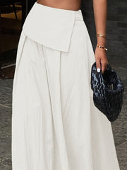 Pleated high-waisted maxi skirt in white with a button detail and a draped overlay.