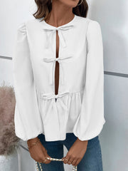 White peplum blouse with keyhole neckline and bow details, long puff sleeves.