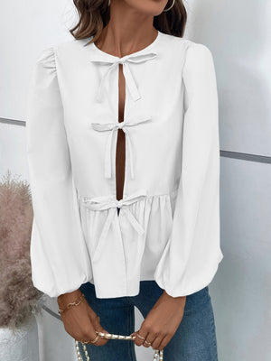 White peplum blouse with keyhole neckline and bow details, long puff sleeves.