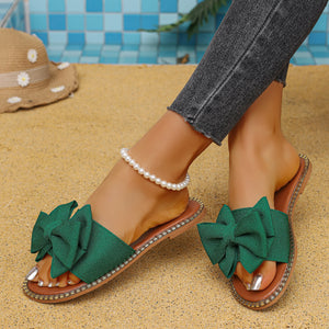 Green bowknot slide sandals with pearl anklet and distressed jeans.
