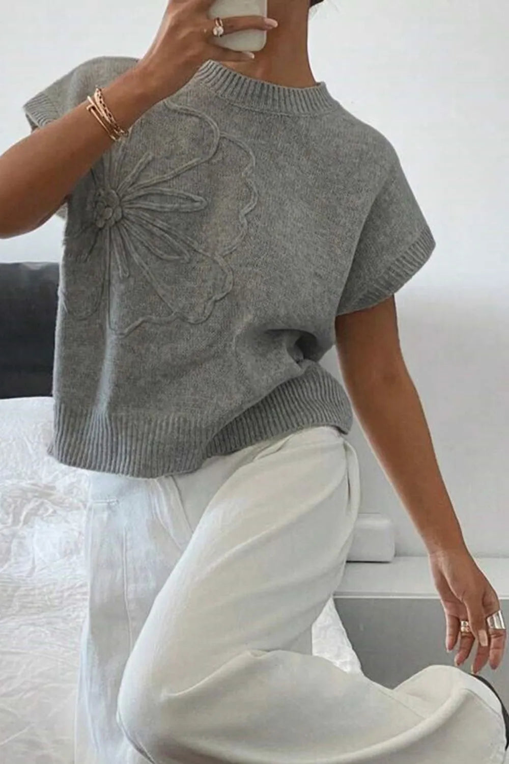 Gray knit top with embroidered flower detail and short sleeves.