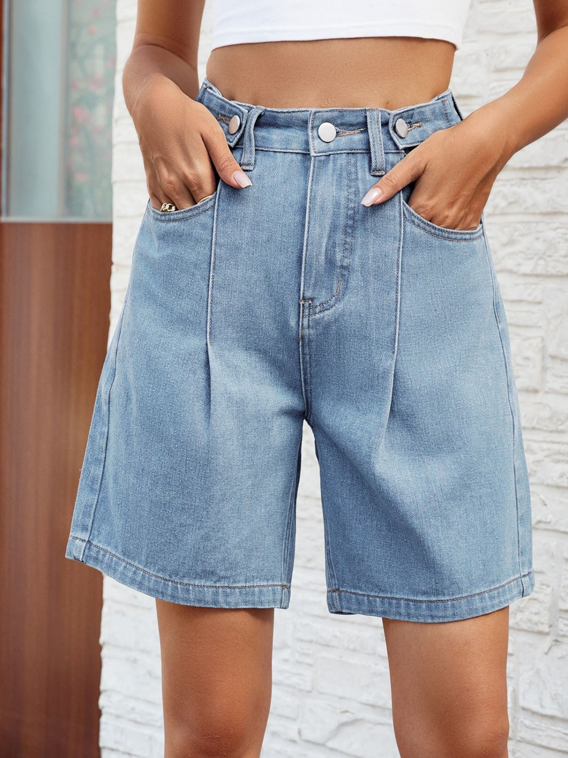 Light wash denim bermuda shorts with front pleats and buttoned closure.