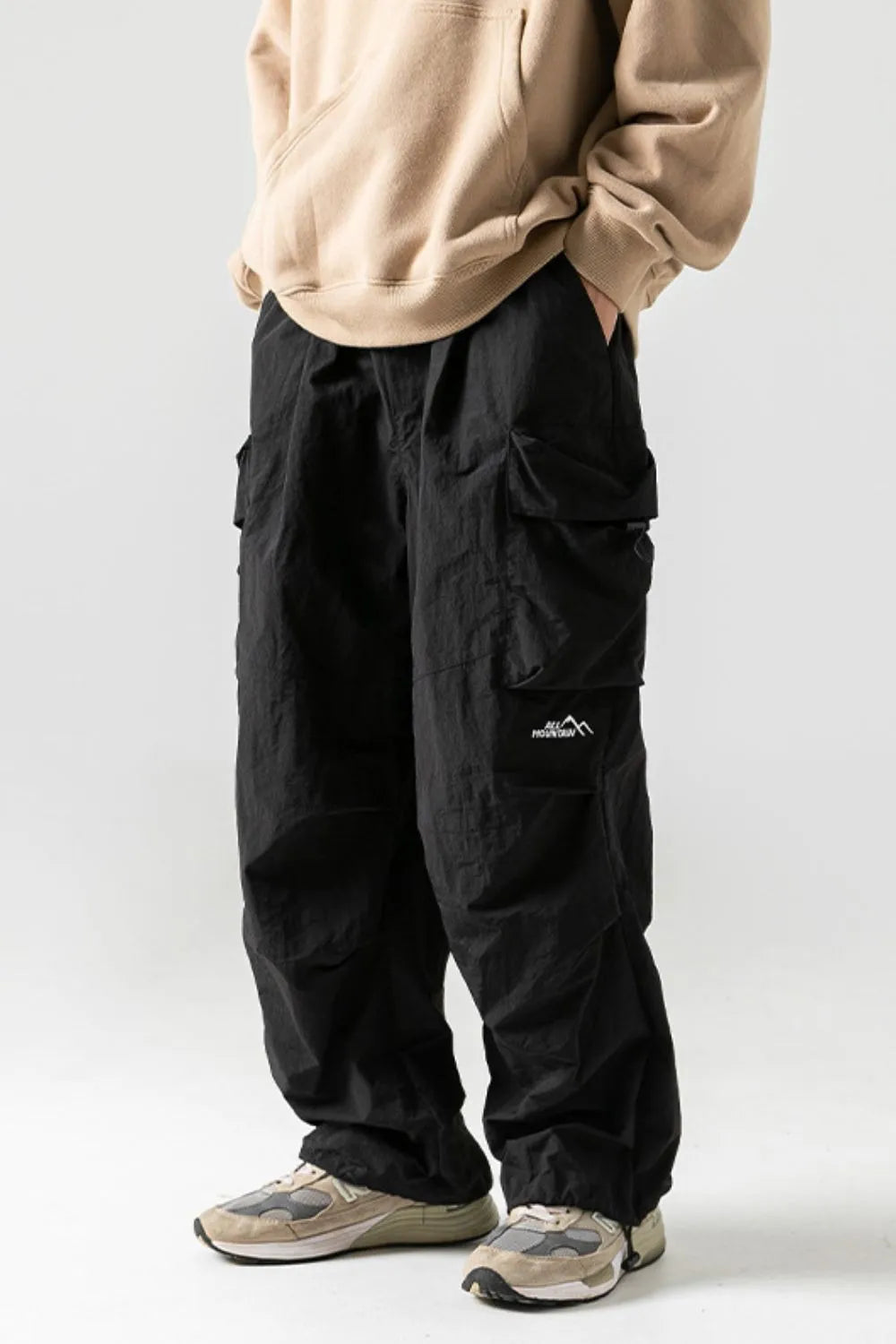 Black oversized cargo pants with multiple pockets and a mountain logo patch.