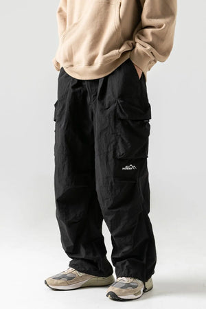 Black oversized cargo pants with multiple pockets and a mountain logo patch.