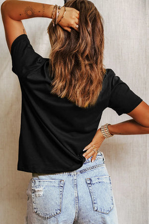 Black graphic tee with short sleeves and a crew neck, styled with denim shorts.