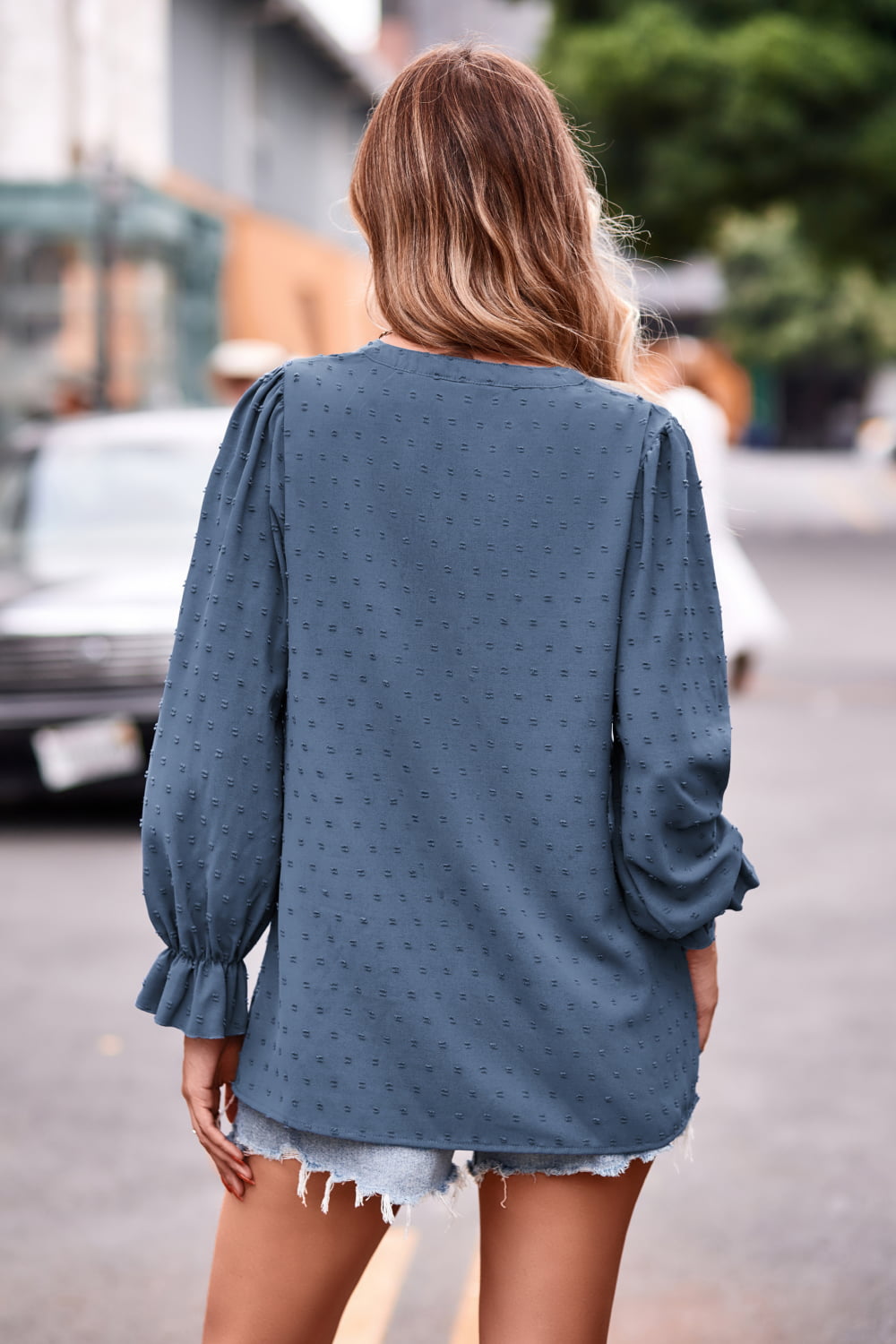 Sky blue textured dot v-neck blouse with ruffle cuffs and long sleeves.