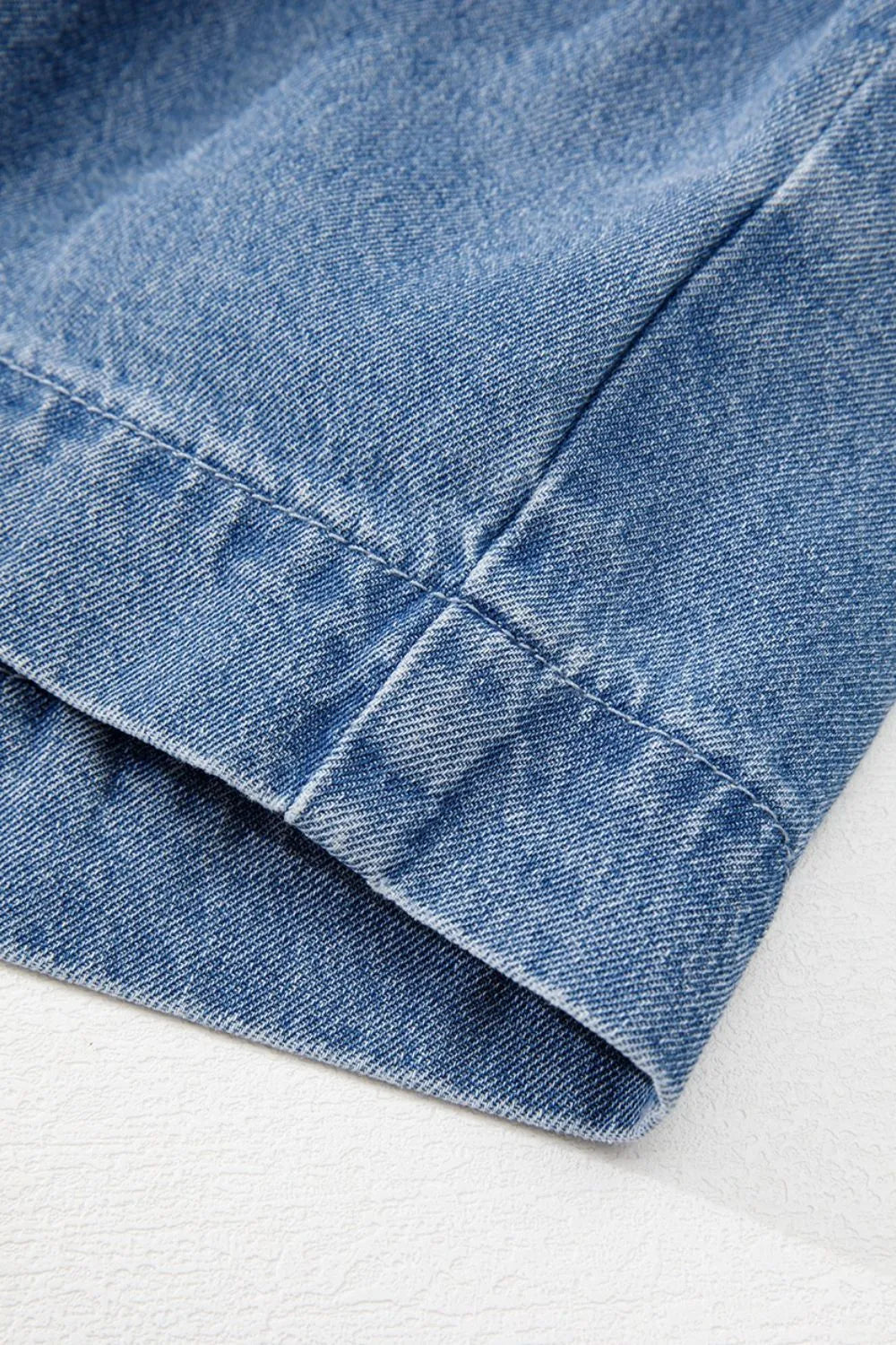 Denim peplum blouse in medium blue with visible stitching detail.
