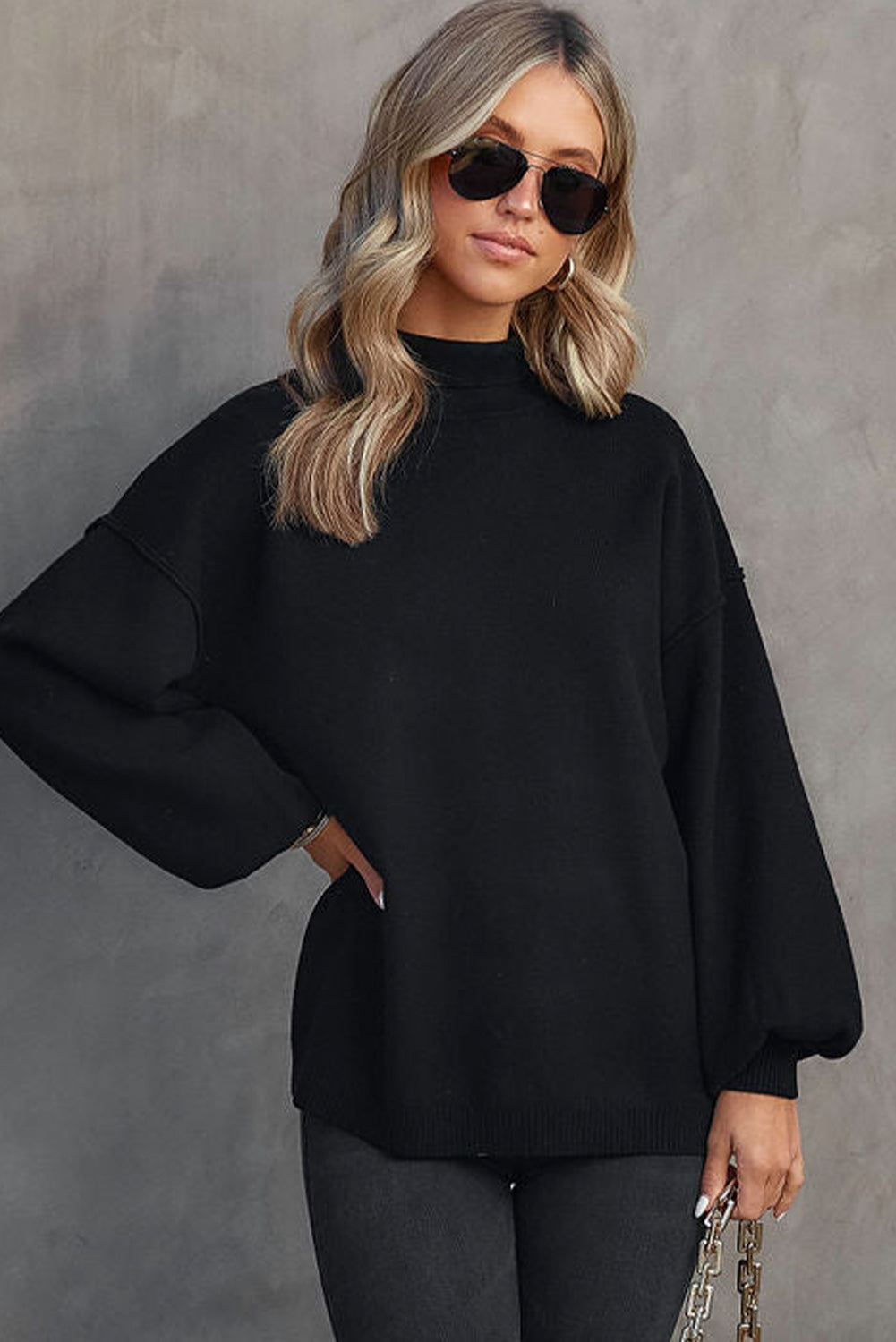 Black knit sweater with mock neck and voluminous balloon sleeves.