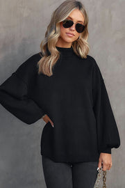 Black knit sweater with mock neck and voluminous balloon sleeves.