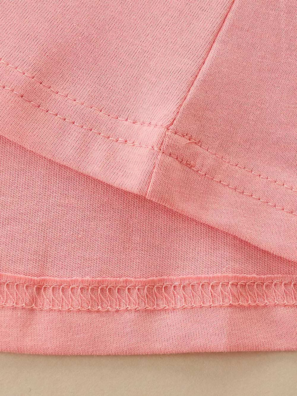 Pink cotton toddler dress detail showing seams and hem.