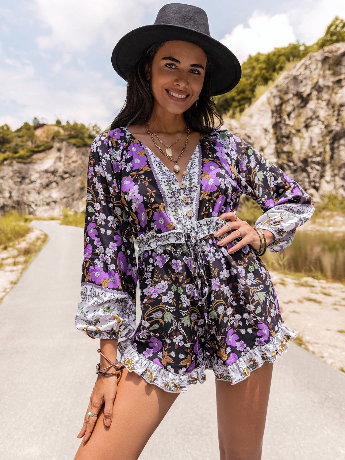 Floral print romper with blouson sleeves, V-neck, button front, and ruffled hem.
