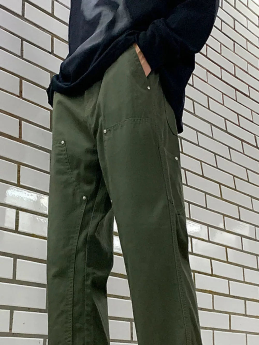 Men's army green relaxed fit cargo pants with silver button details and utility pockets.