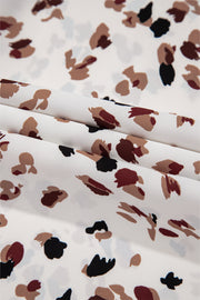 White abstract print blouse with a high neck, featuring a scattered animal-like pattern.