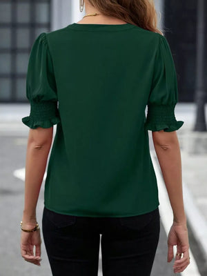 Sophisticated green blouse with puffed sleeves and smocked cuffs.