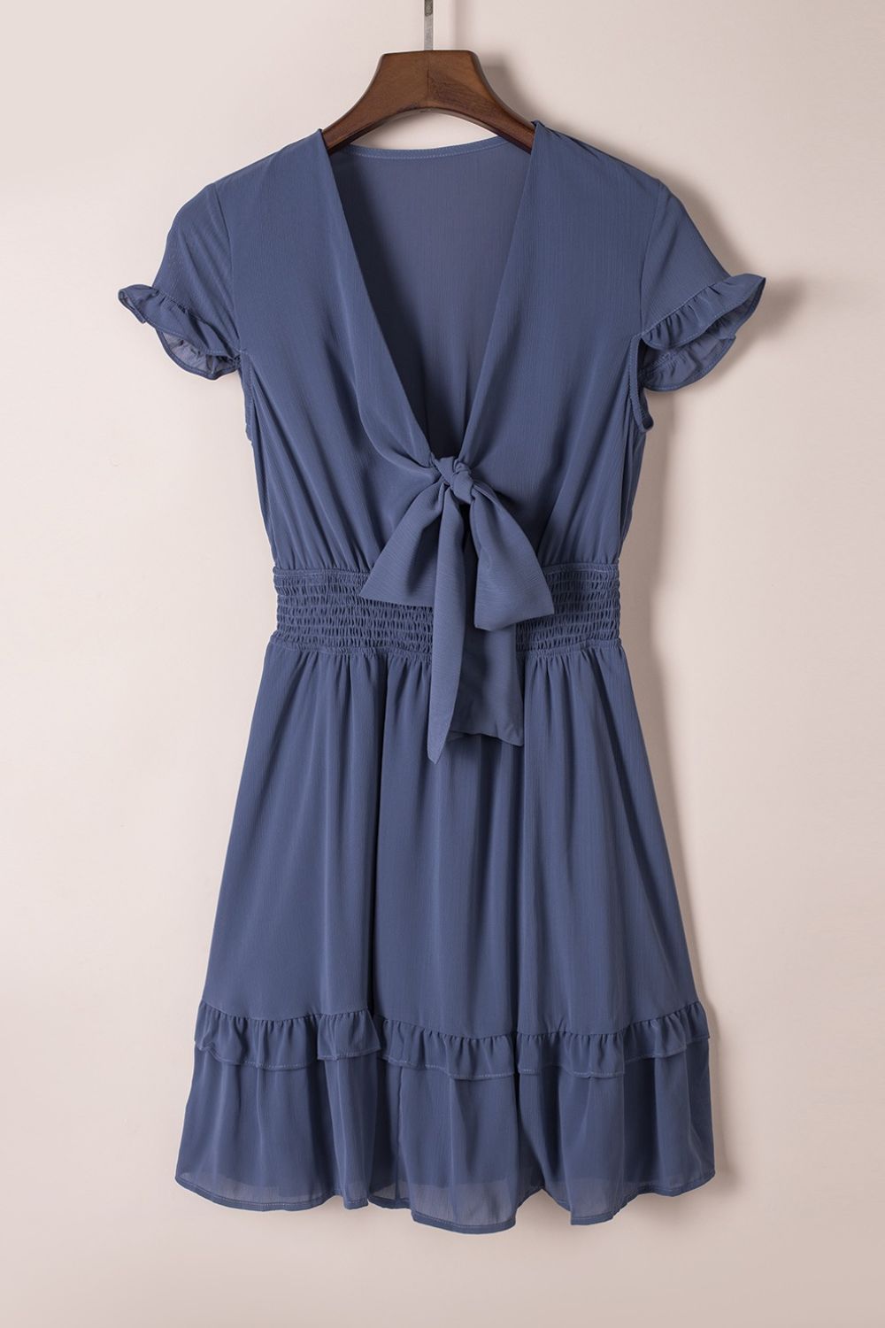 Dusty blue ruffled bow-tie V-neck mini dress with smocked waist and tiered ruffled hem.