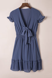 Dusty blue ruffled bow-tie V-neck mini dress with smocked waist and tiered ruffled hem.