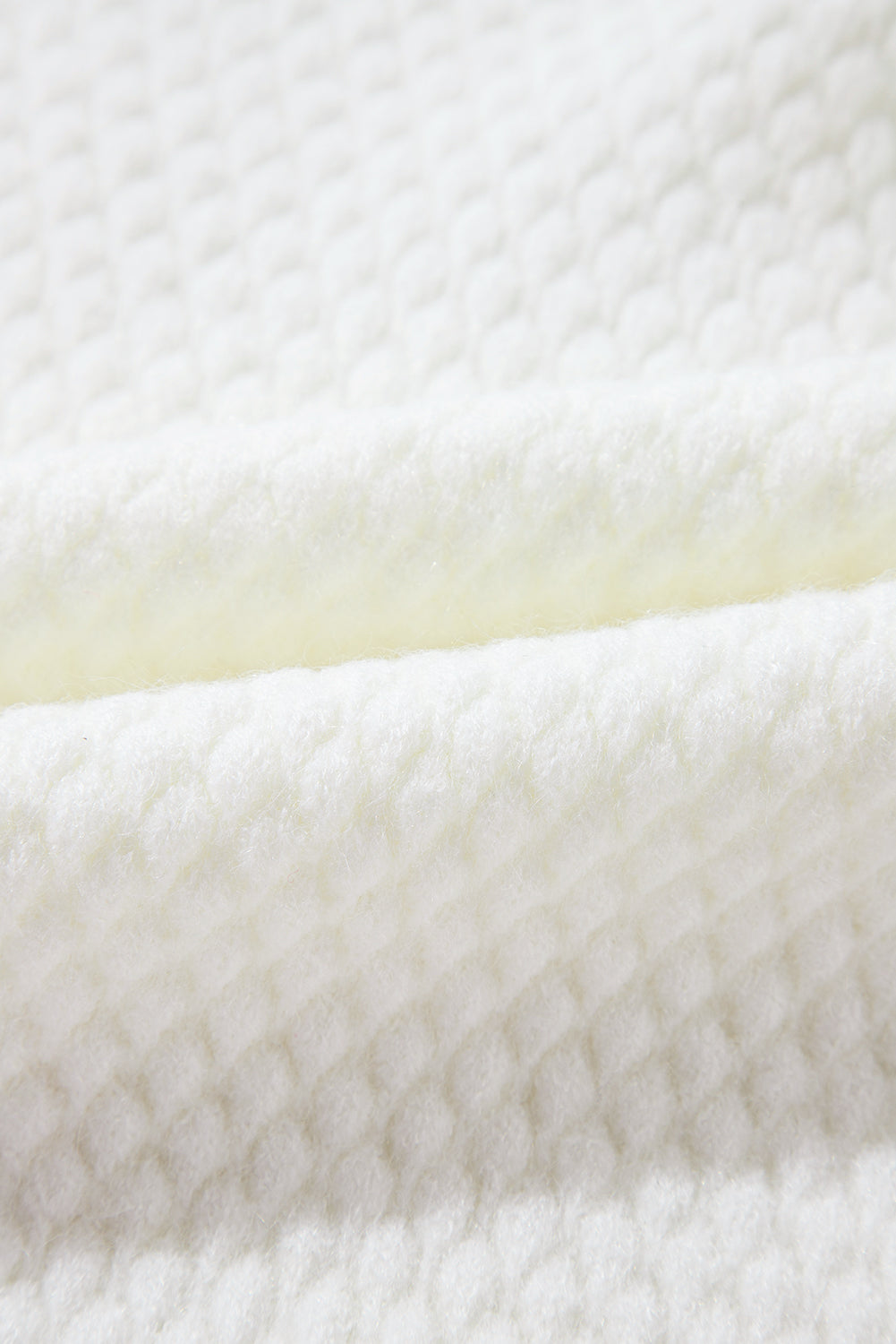 White knit sweater with a textured diamond pattern, made of acrylic.