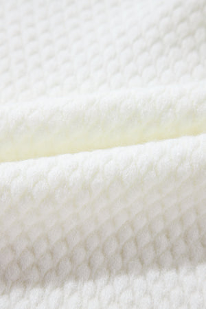 White knit sweater with a textured diamond pattern, made of acrylic.