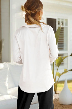 White satin blouse with poet sleeves and buttoned front, styled casually.