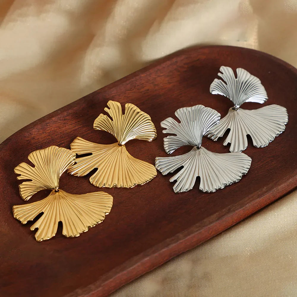 Ginkgo leaf statement earrings in gold and silver with ribbed texture.