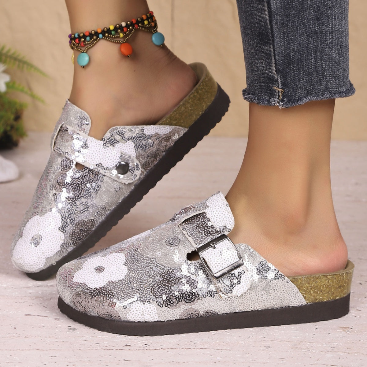 Sparkling sequin slip-on mules in white with decorative buckle and cork sole.