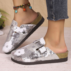 Sparkling sequin slip-on mules in white with decorative buckle and cork sole.