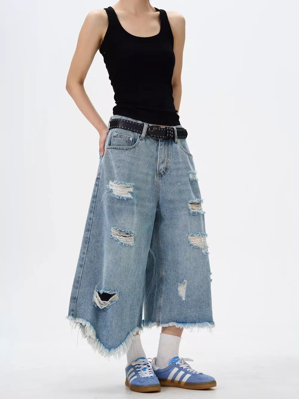 Distressed light wash denim wide-leg jeans with raw hem and ripped details.