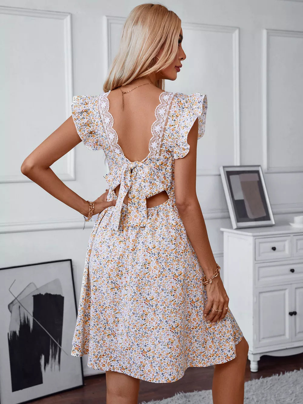 Ditsy floral mini dress with ruffled sleeves, lace trim, and back tie detail.