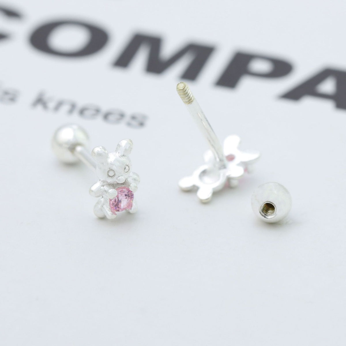 Silver bear stud earrings with pink zircon stone detail.