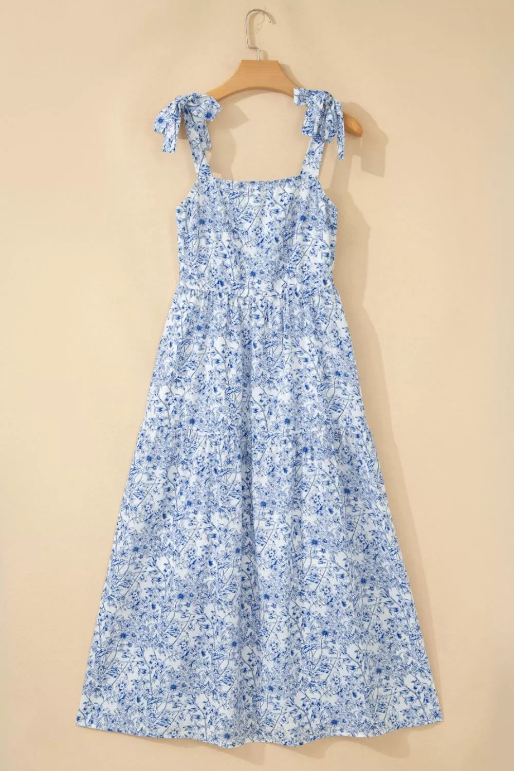 Maxi dress with blue floral print, square neck, tie straps, and tiered skirt.