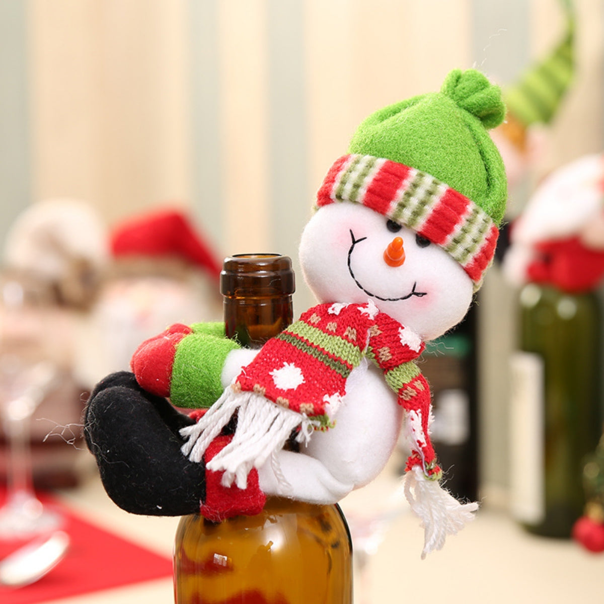 Festive snowman bottle hugger in green hat and red scarf with white polka dots.