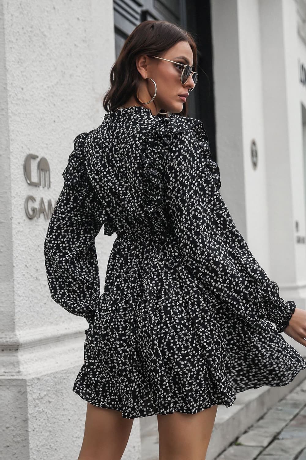 Black dot print dress with ruffle trim, long sleeves, and cinched waist.