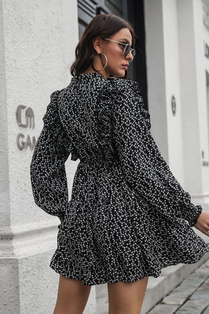 Black dot print dress with ruffle trim, long sleeves, and cinched waist.