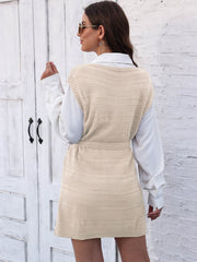 Cream knit vest dress with tie and slit, styled over a white shirt.