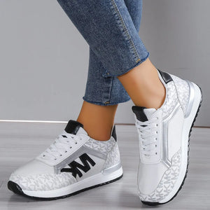 White and silver monogram runner sneakers with black accents and logo detail.