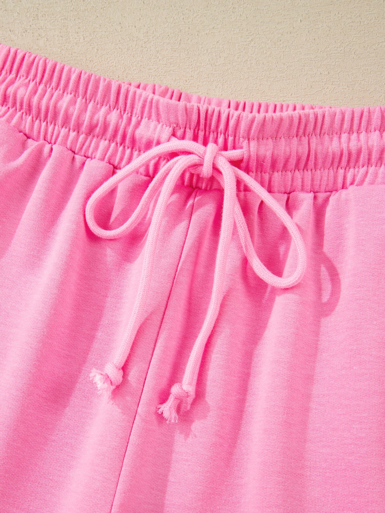 Pink cotton bikini bottoms with elastic waistband and drawstring detail.