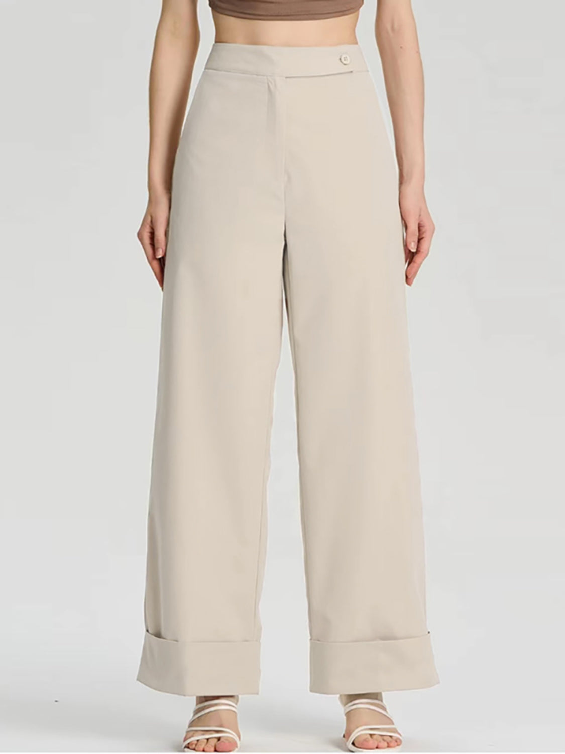 Beige wide-leg tailored trousers with cuffed hemline and button detail.