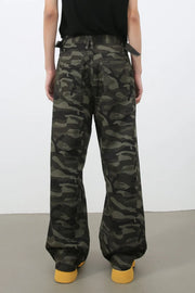 Wide-leg camo denim trousers in black with adjustable waist straps and yellow shoes.