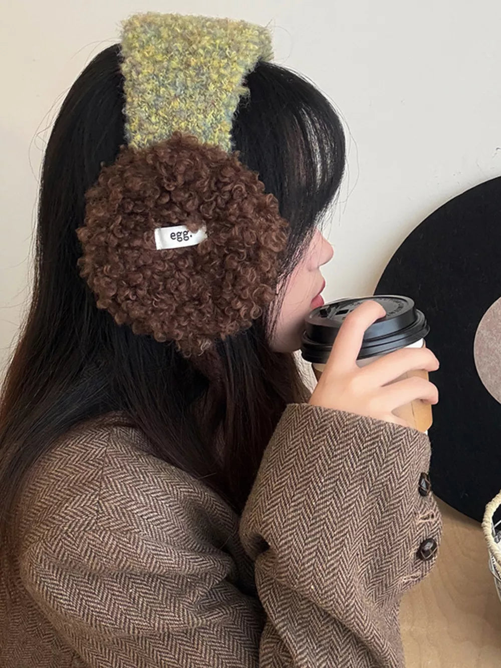 Plush sherpa earmuffs with textured green headband and brown earcups.