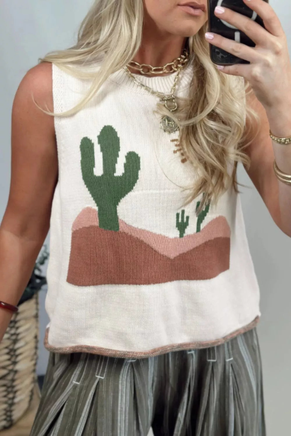 Cream knit sweater vest with a desert cactus graphic and a crew neck.
