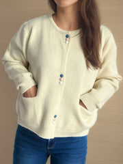 Cream ribbed knit button-up cardigan with colorful accent buttons and pockets