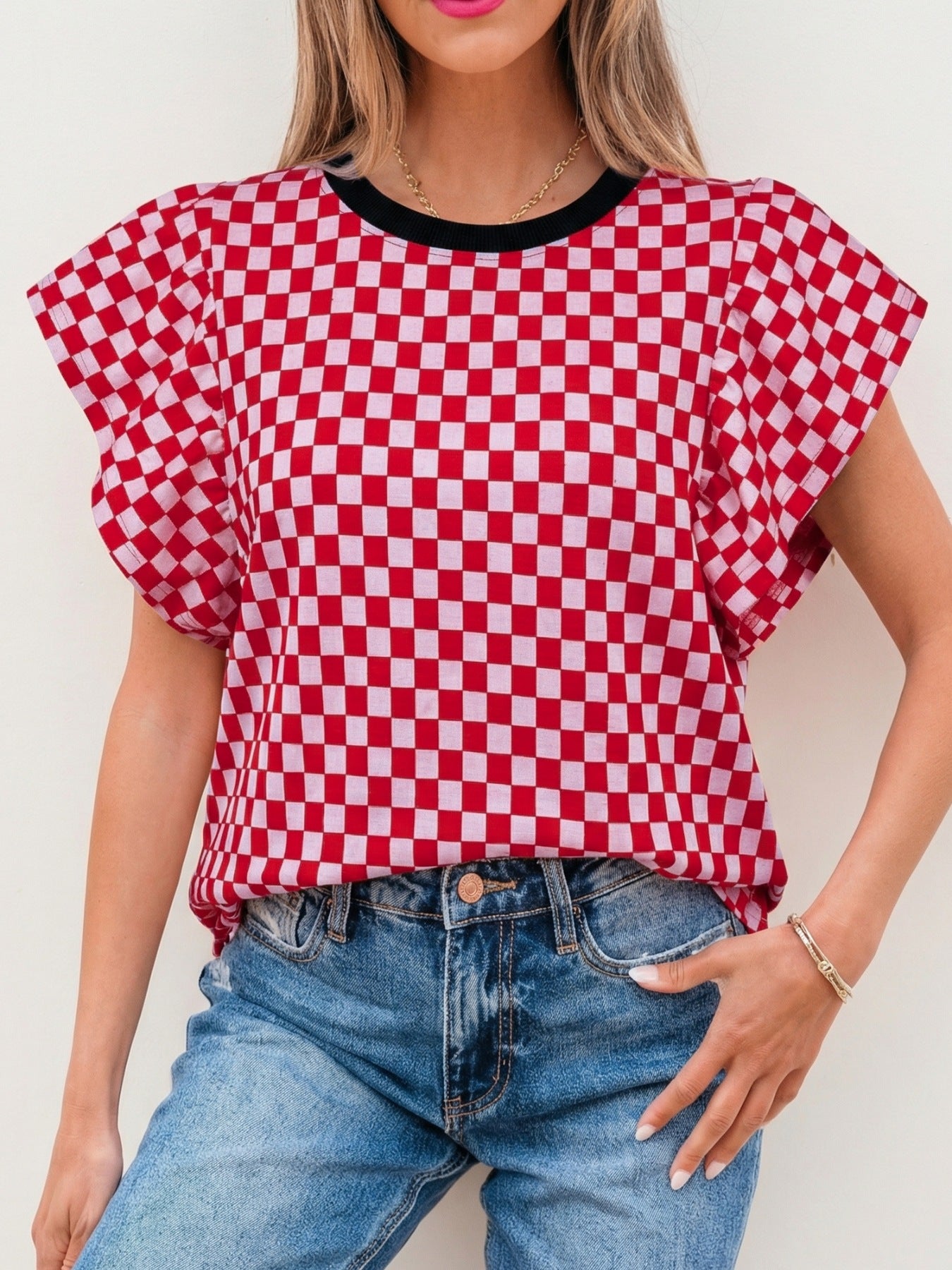 Red and white checkered print shirt with ruffle sleeves and black neckline.
