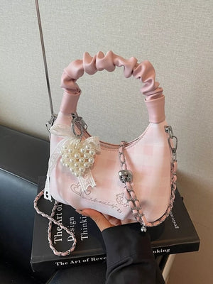 Blush pink ruched handle crossbody bag with pearl heart charm and chain strap.
