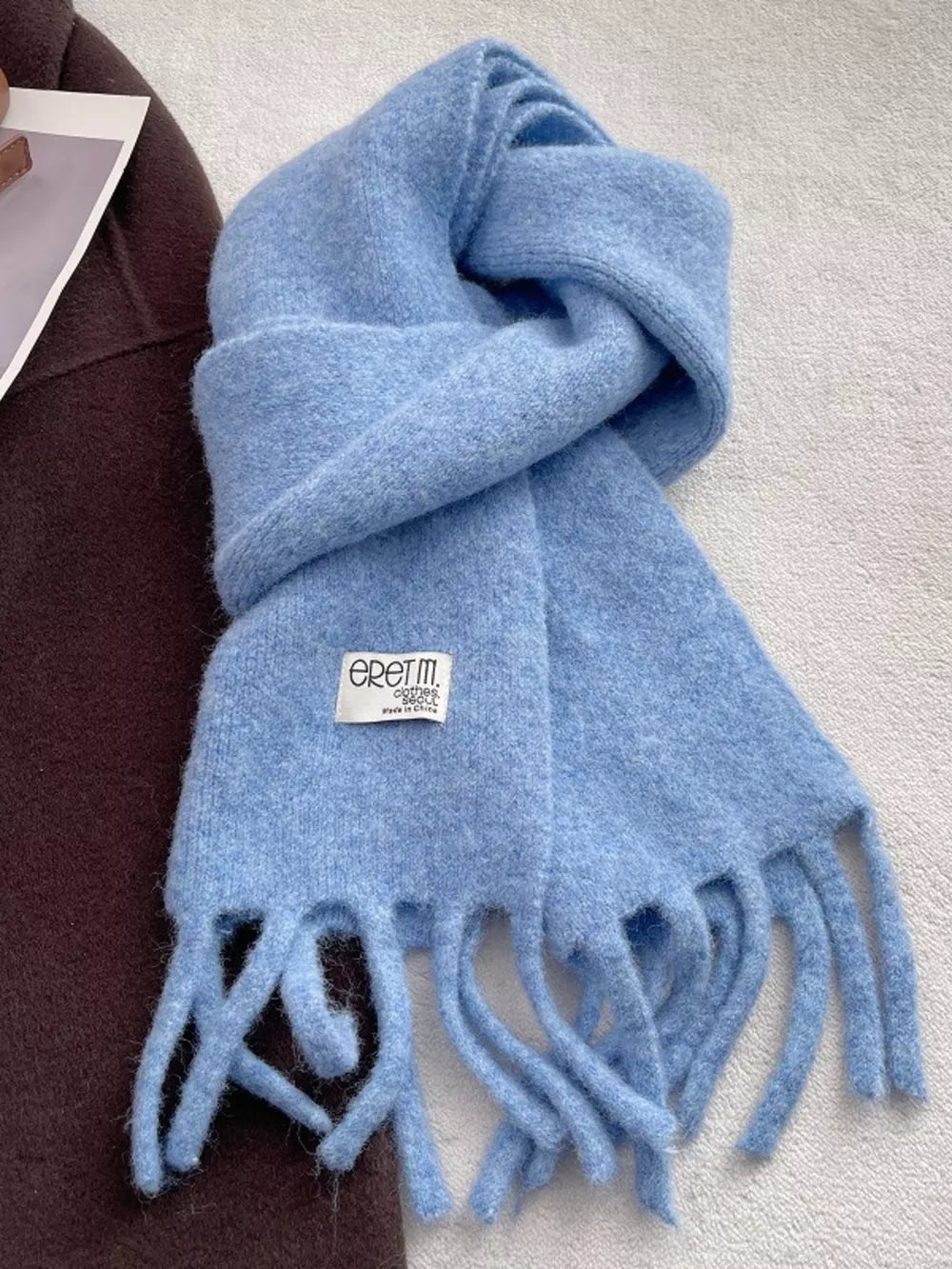 Plush fringe scarf in sky blue with a solid design and cozy texture.