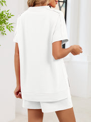 Relaxed white two-piece set with short sleeves, crew neck, and side pockets on shorts.