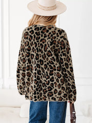 Leopard print fuzzy cardigan with long sleeves and pockets, styled with jeans and a hat.