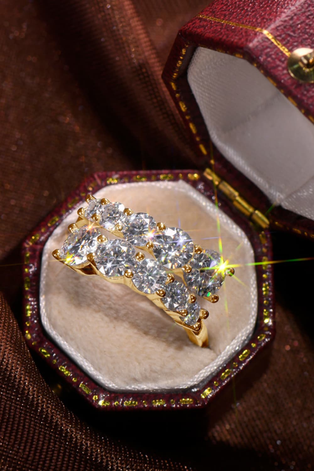 Gold cascading cluster diamond ring with two rows of sparkling stones in a jewelry box.