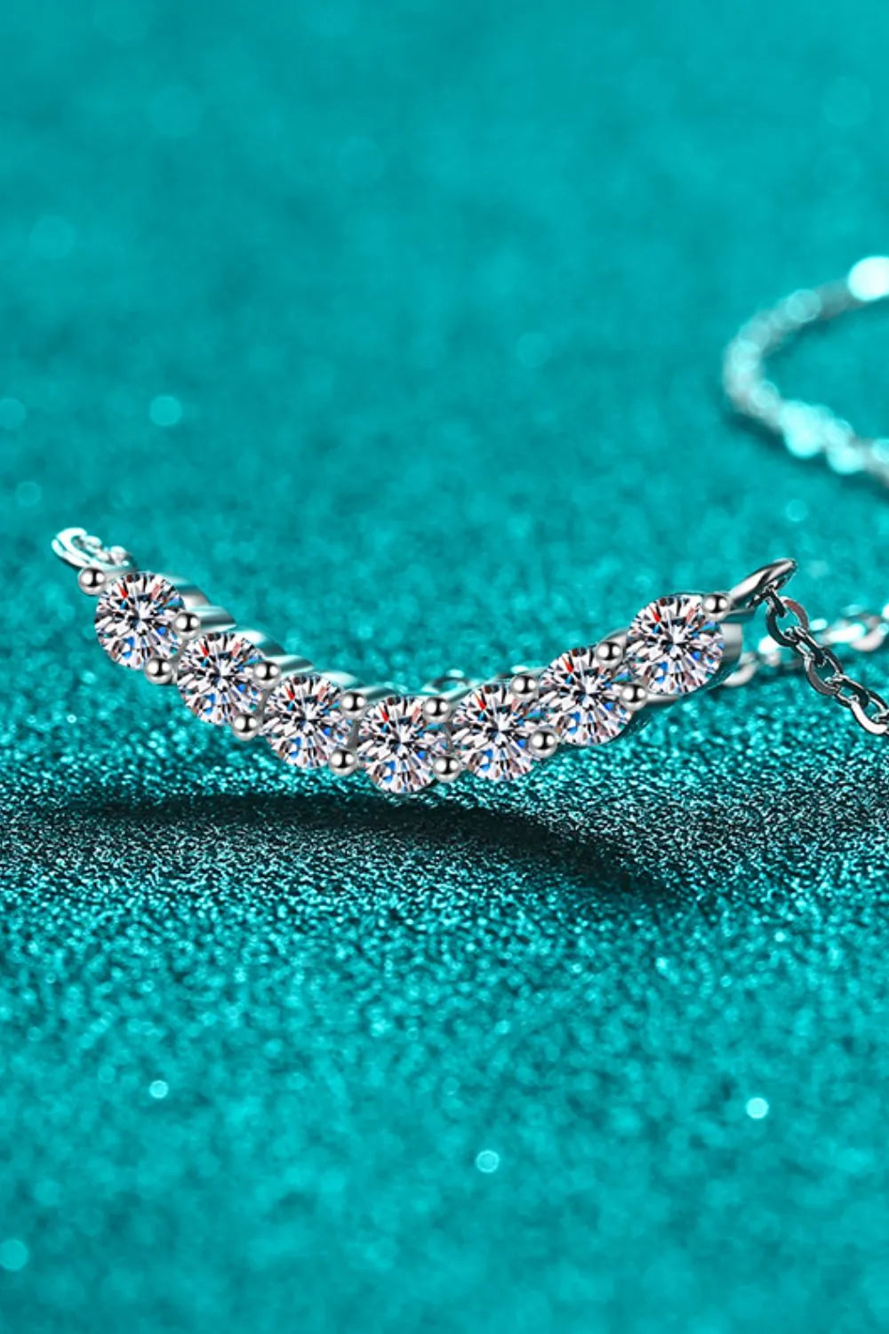 Silver necklace with a curved row of seven sparkling moissanite stones.